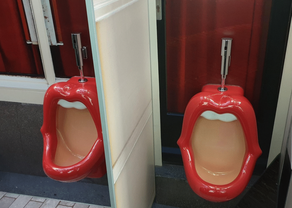Two men's urinals shaped like mouths with bright red lipstick in Amsterdam red light district tour area