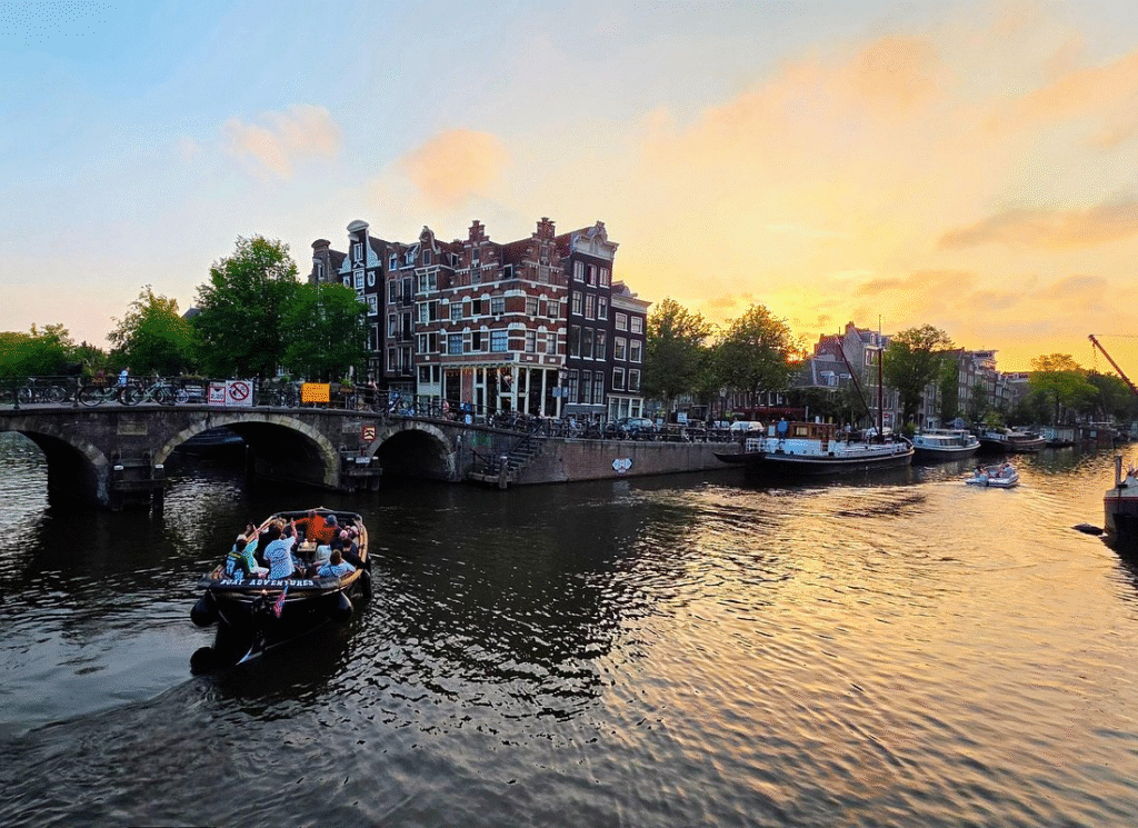 Small group of travelers chatting with local guide on intimate amsterdam evening canal cruise through quiet Jordaan waterways