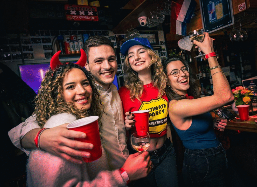 Party group on Amsterdam red light district pub crawl visiting traditional brown cafés at evening