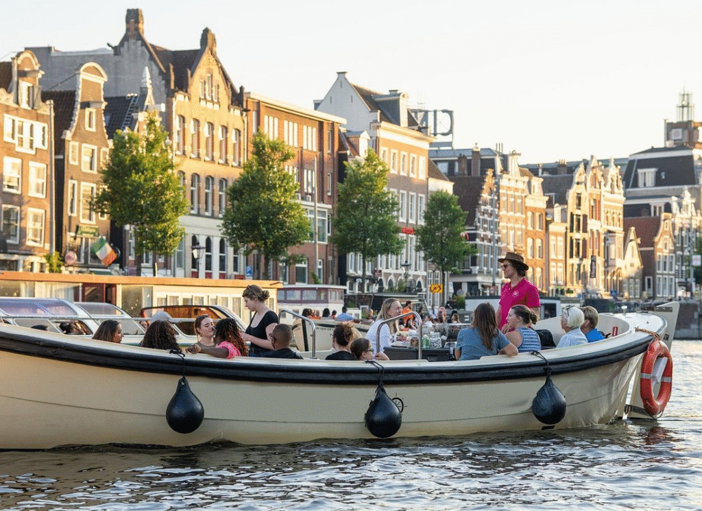 A small group sharing drinks on intimate amsterdam evening canal cruise with cozy boat seating and canal houses in background