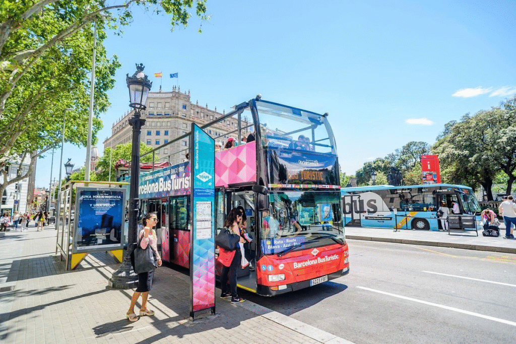 Open top double decker hop on hop off Barcelona bus with families enjoying panoramic city views during daytime tour