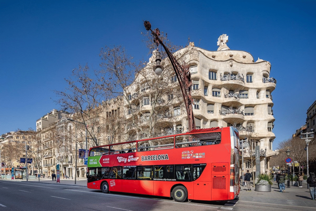 Tourists on hop on hop off Barcelona bus with Gaudi designed buildings in background