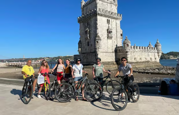 Cyclists riding from Lisbon city center toward Belém Tower on a historic bike tour route