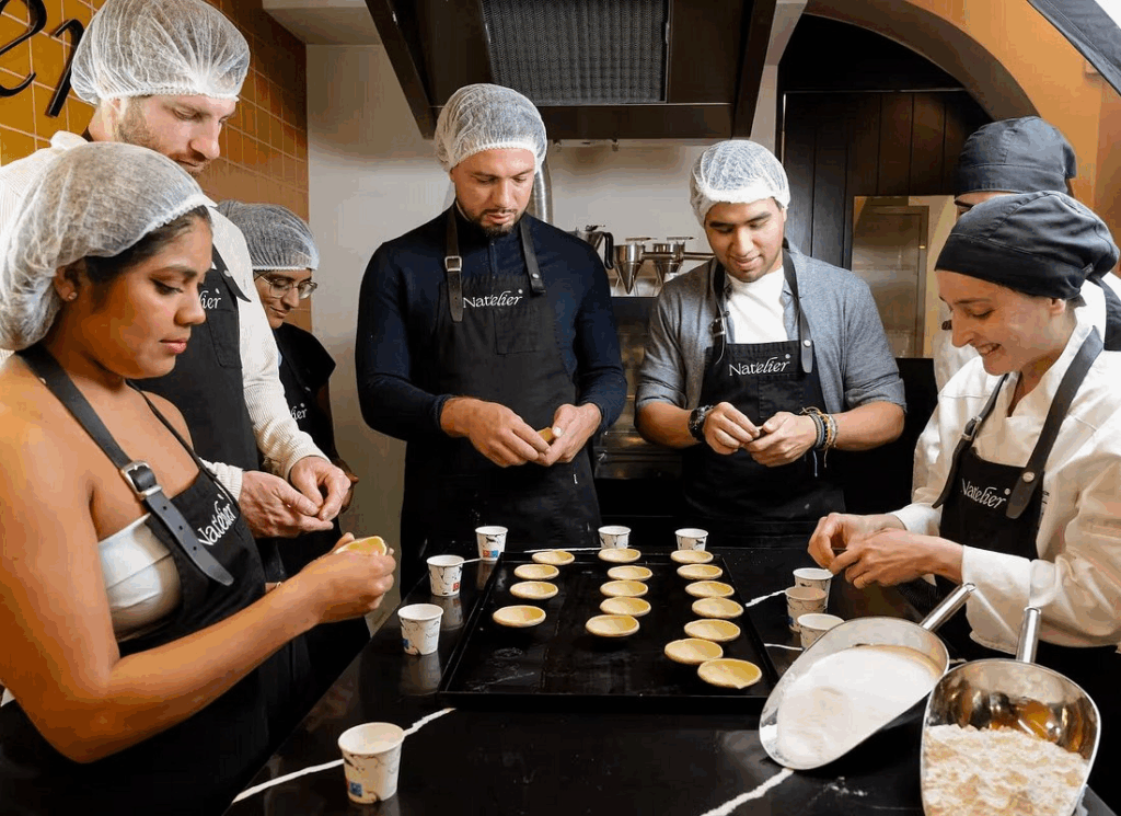 Solo travelers mastering pastel de nata cooking class Lisbon during afternoon culinary session