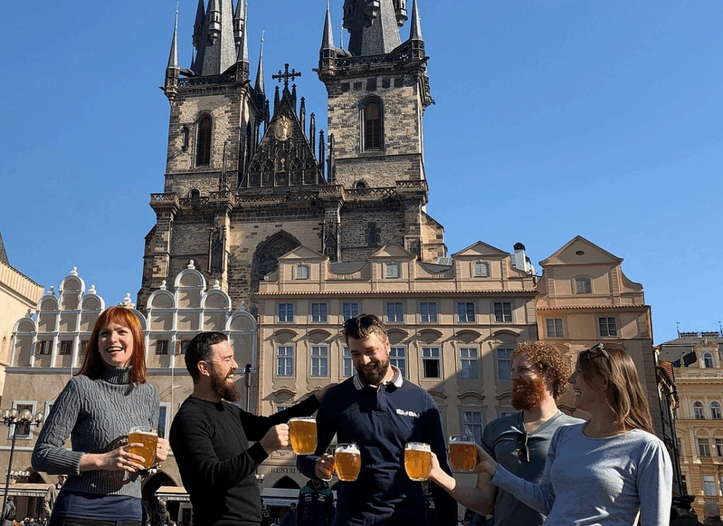 Friends enjoying Czech beer and stories at a historic Prague pub during an afternoon tour experience