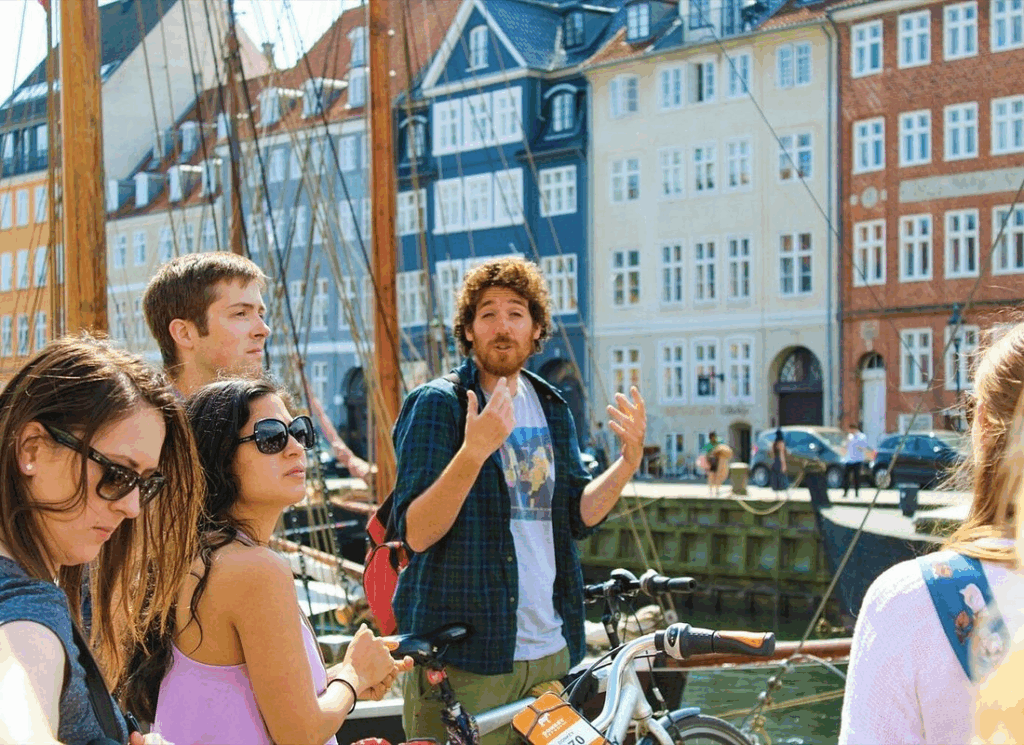Tour guide explaining Nyhavn harbor highlights during a copenhagen bike tour with colorful waterfront buildings.