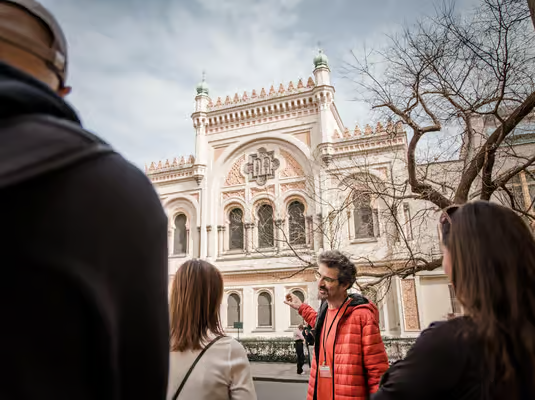 Prague Jewish Quarter walking tour with a local guide explaining history outside a historic synagogue, as visitors gather in the Jewish Quarter