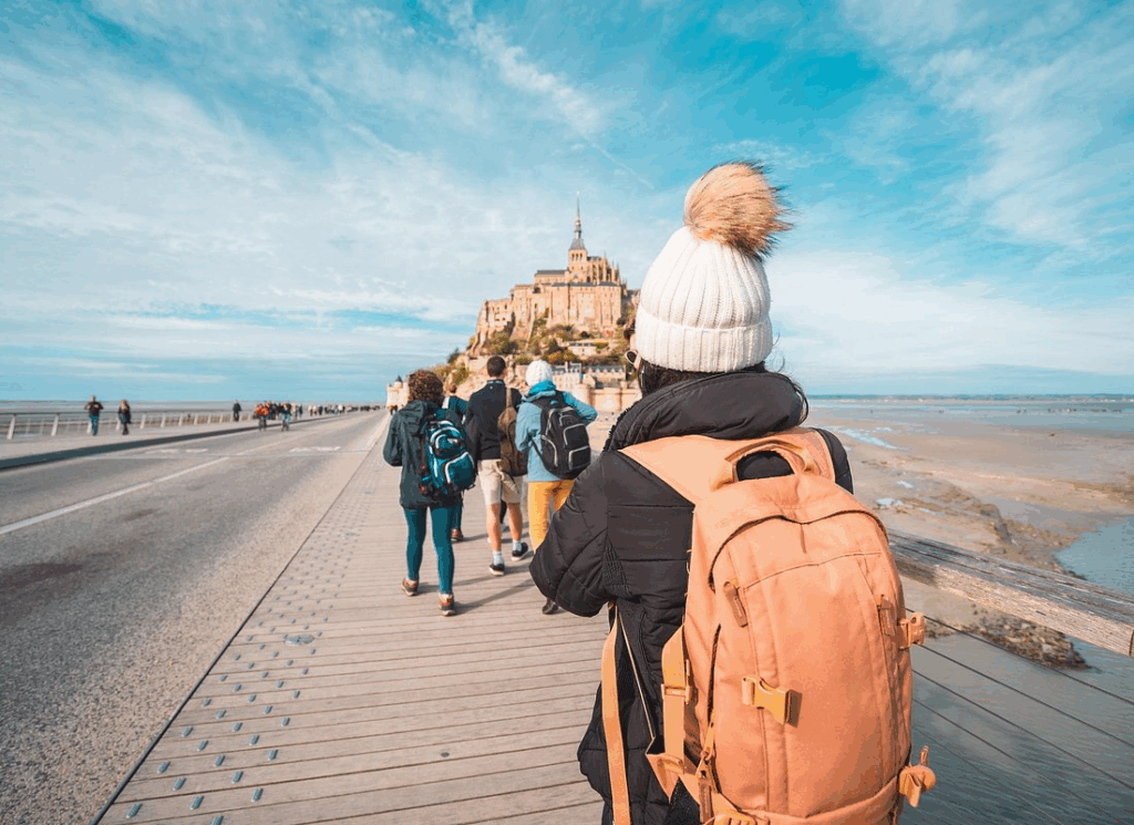 Travelers on Mont Saint Michel tours walking medieval pathways toward the island abbey