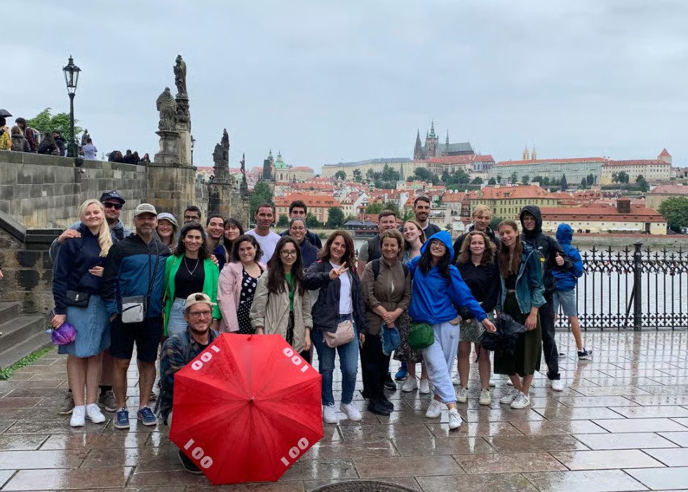 Travel group exploring Charles Bridge with Prague Castle rising majestically in the background during a prague walking tour