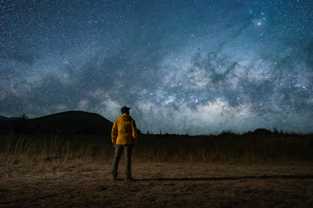 A visitor gazes up at the Milky Way stretching across the night sky, an unforgettable sight often experienced on mauna kea stargazing tours in Hawaii