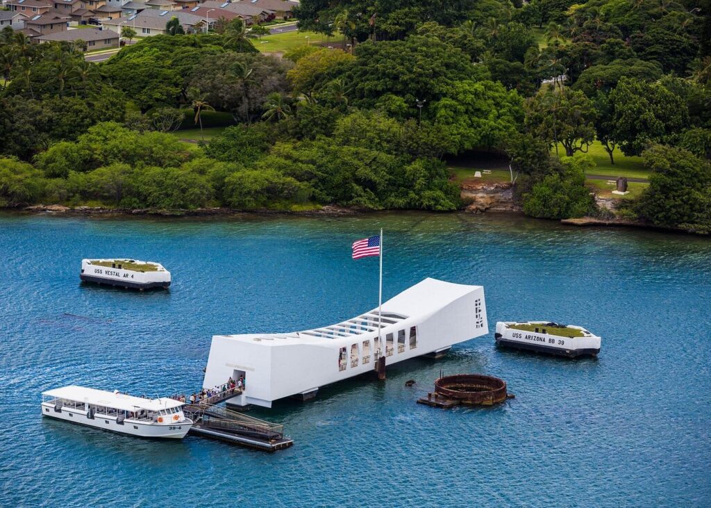 Pearl Harbor tours visiting the USS Arizona Memorial with American flag flying above the historic battleship site in Honolulu Harbor.
