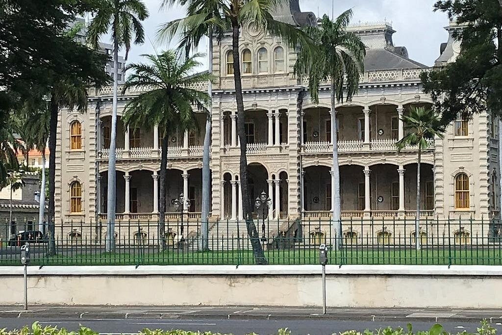 Historic Iolani Palace in downtown Honolulu surrounded by palm trees, a popular cultural stop included on many pearl harbor tours in Oahu.