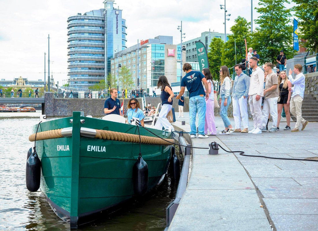 passengers boarding an amsterdam open boat canal cruise at a city dock near the waterfront