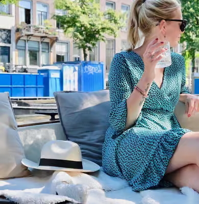 woman relaxing with a drink on an amsterdam open boat canal cruise through sunny city canals