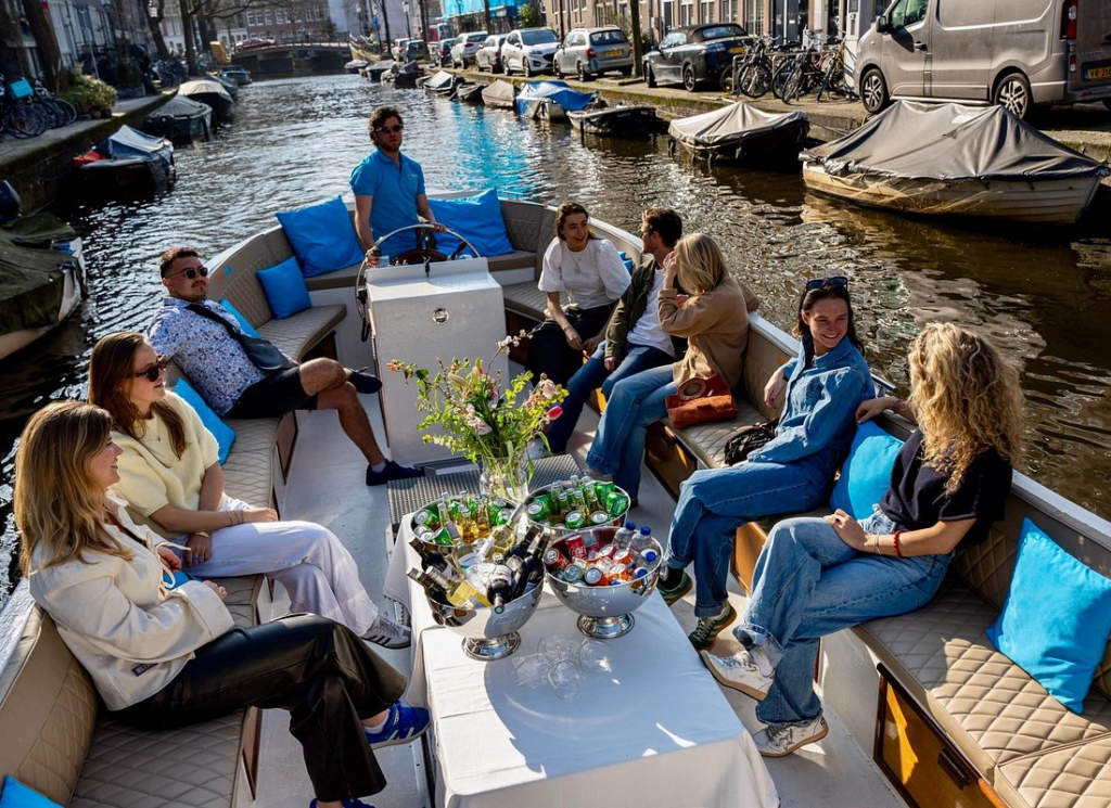 group enjoying drinks on an amsterdam open boat canal cruise through a picturesque city canal