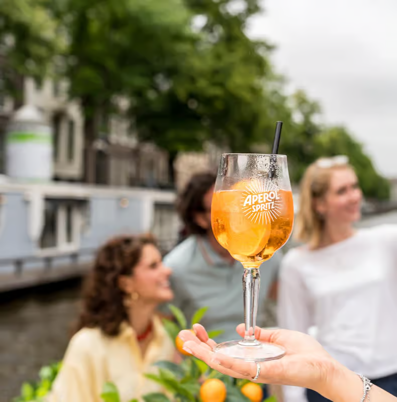 aperol spritz served on an amsterdam open boat canal cruise with guests and canal views in background